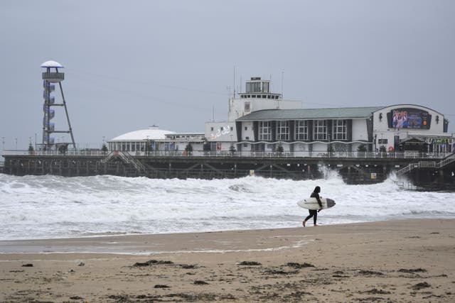 A surfer makes their way out of the sea on Bournemouth beach in Dorset (Andrew Matthews/PA)