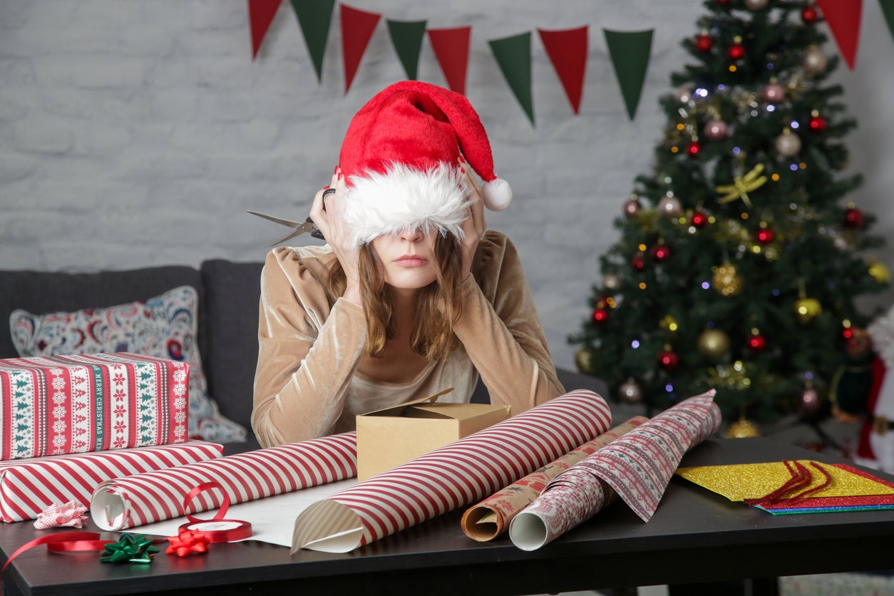 <p>Depressed frustrated woman wrapping Christmas gift boxes, winter holiday stress concept</p>