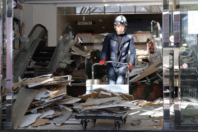 <p>A worker clears debris after an earthquake in Hachinohe City, Aomori Prefecture</p>