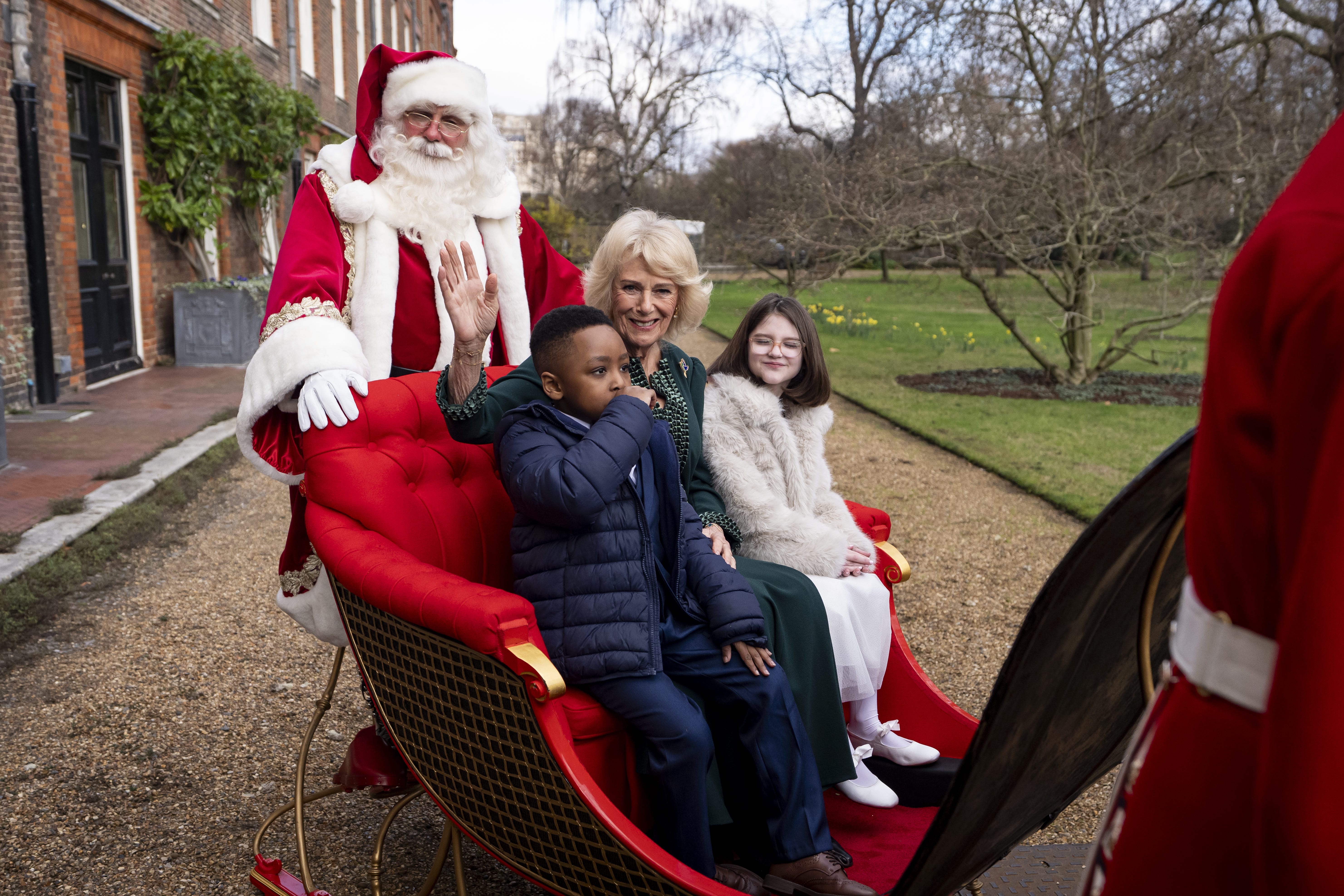 A person dressed as Father Christmas, the Queen, Samuel (left) and Myla (right) on the State Sleigh in the gardens of Clarence House (Aaron Chown/PA)
