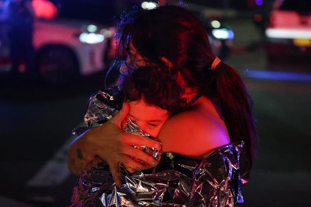<p>A woman holds her baby in a blanket after the mass shooting at Bondi Beach in Sydney on Sunday</p>