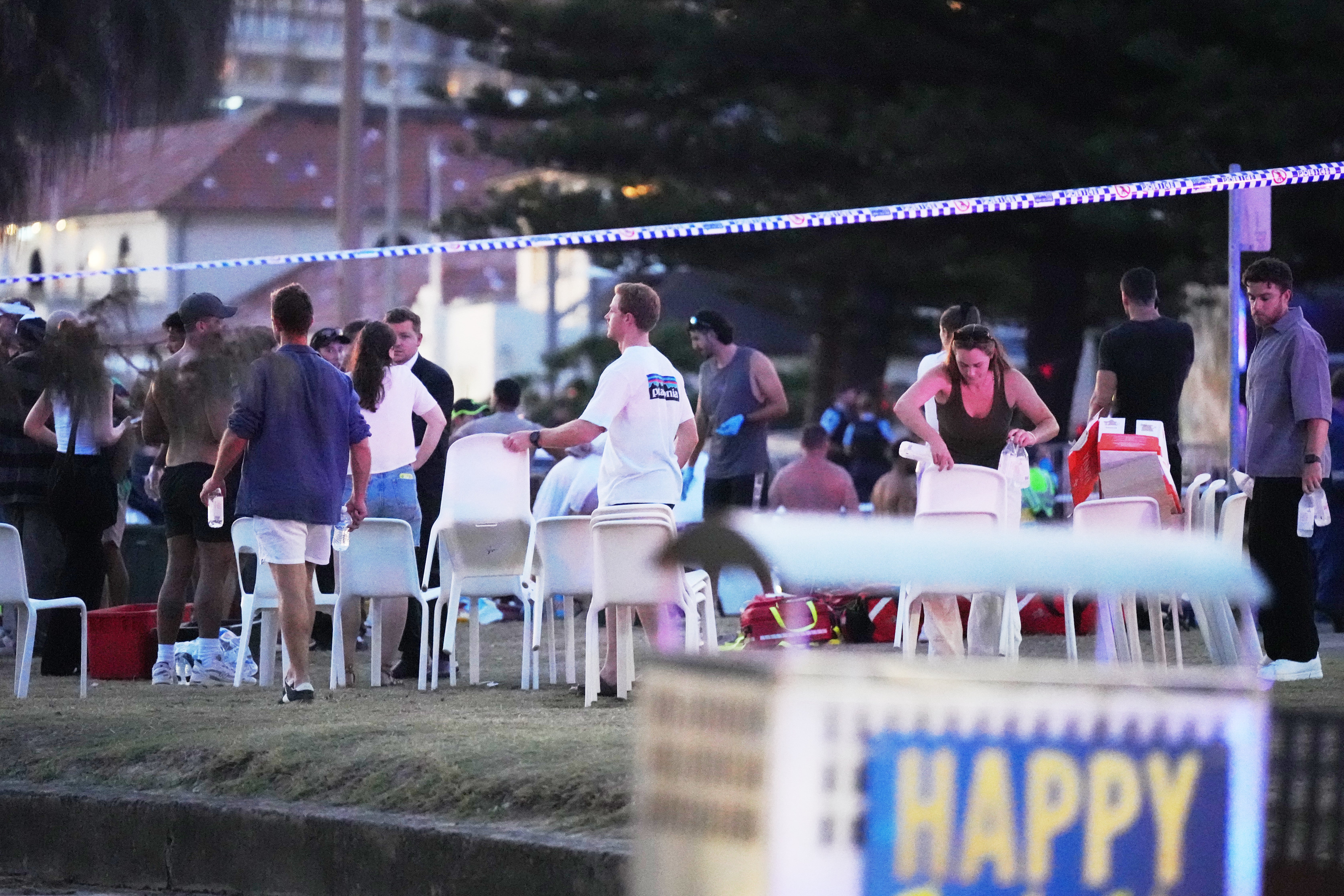 <p>People and emergency workers gather at location where a holiday event was taking place and then a reported shooting at Bondi Beach in Sydney</p>