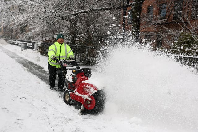 <p>A municipal employee removes snow in a street as the snow falls in the Brooklyn borough of New York City</p>