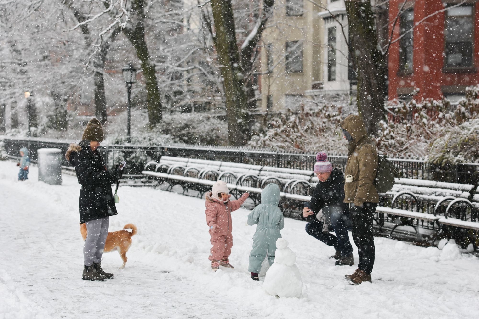 Children play on a snow-covered street as snow falls down in the Brooklyn borough of New York City