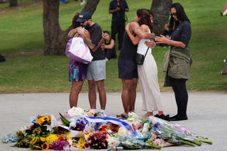 People embrace at a flower memorial placed outside Bondi Pavilion at Sydney’s Bondi Beach, Monday