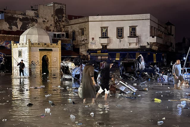 <p>People wade through a square after a flash flood in Safi on December 14, 2025</p>