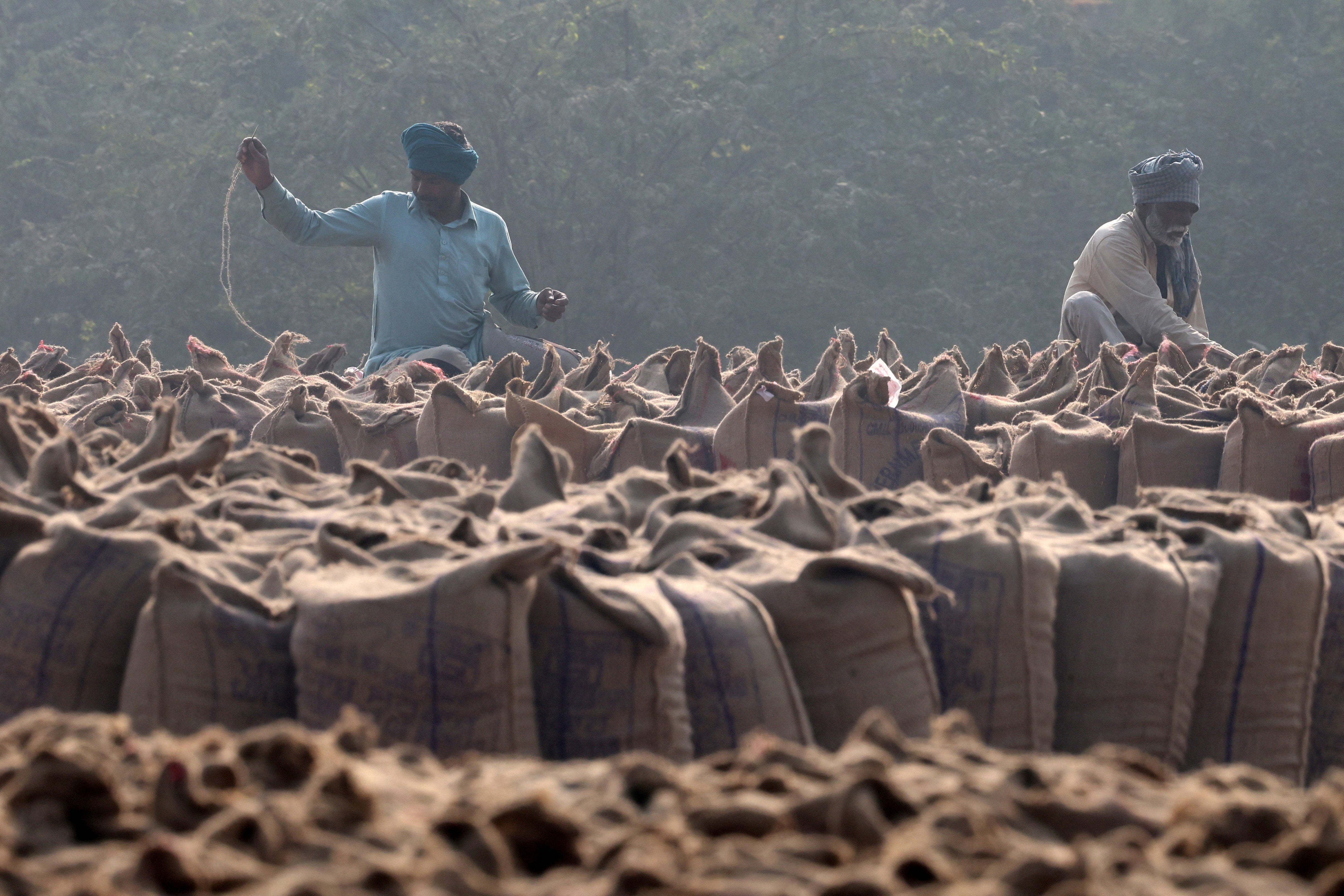<p>Workers sew sacks of rice grains in a grain market at Mansa</p>