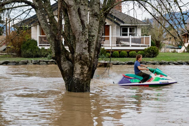 <p> Justus Top, 13, rides a jet ski through his family's front yard Saturday, Dec. 13, 2025 in Sedro-Wooley, Wash. Water from the nearby Skagit River flooded the garage but spared the house, coming within a foot of the structure</p>