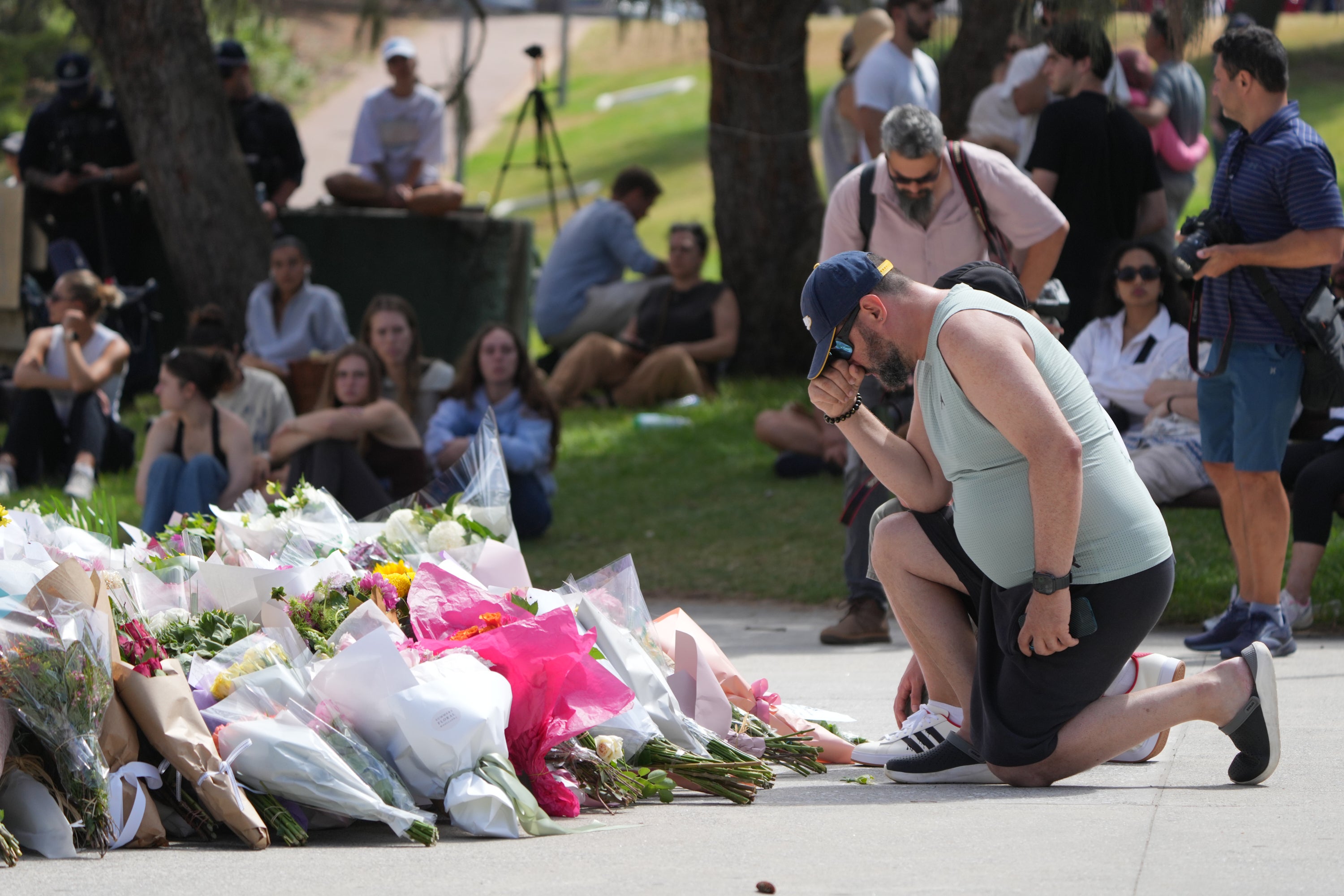 A man kneels after laying flowers at a memorial outside the Bondi Pavilion at Sydney's Bondi Beach, Monday, 15 December 2025, a day after a shooting