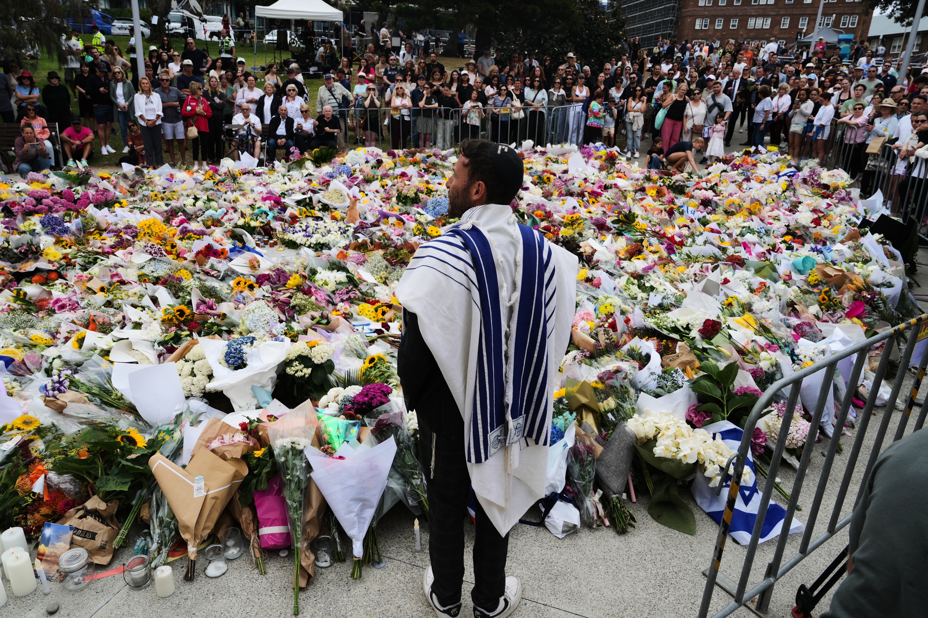 <p>Rabbi Yossi Friedman speaks to people gathering at a flower memorial by the Bondi Pavilion at Bondi Beach on Tuesday, 16 December 2025, following Sunday’s shooting in Sydney, Australia</p>