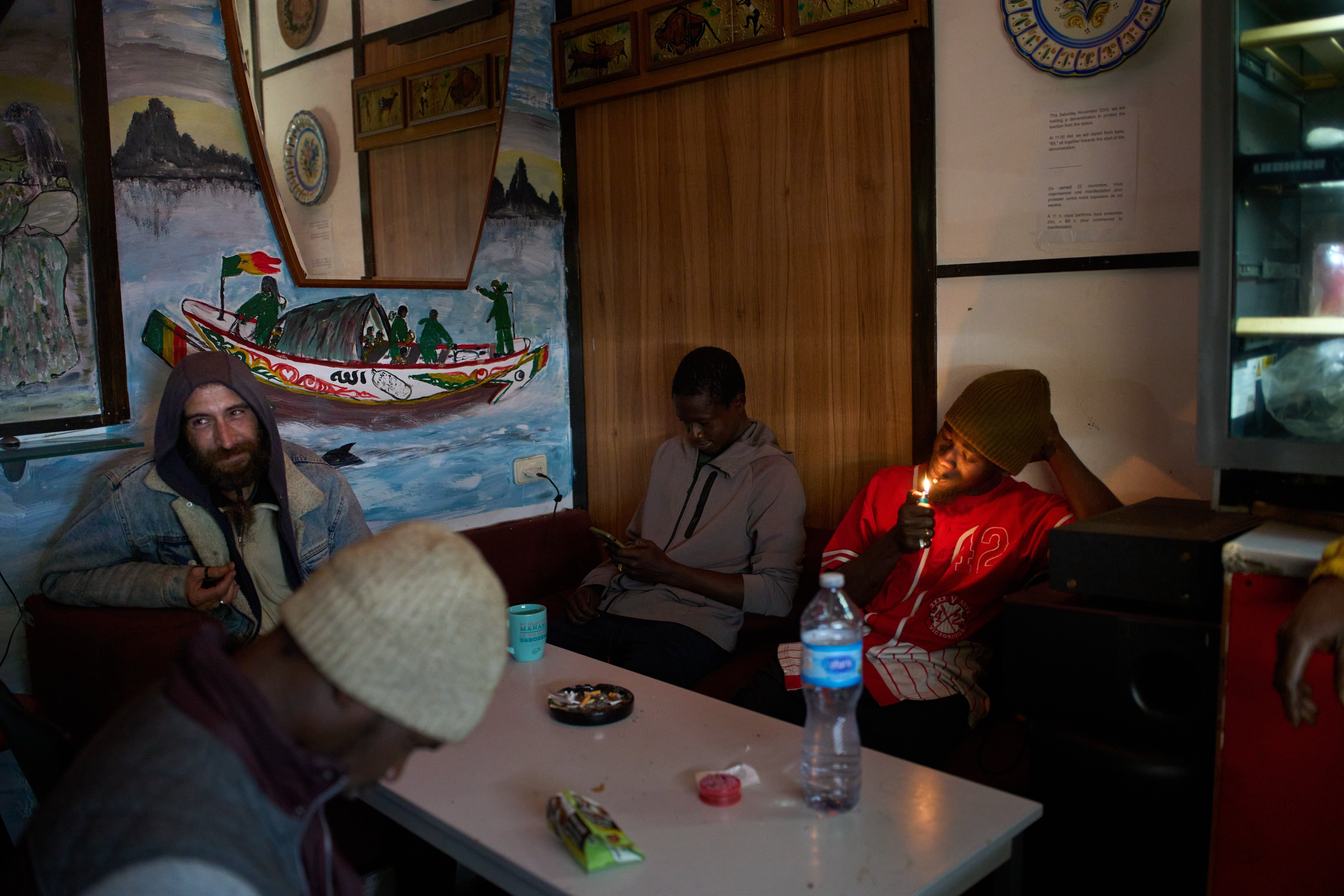 Migrants from Romania and Senegal sit in a makeshift bar inside an abandoned school in Badalona, near Barcelona