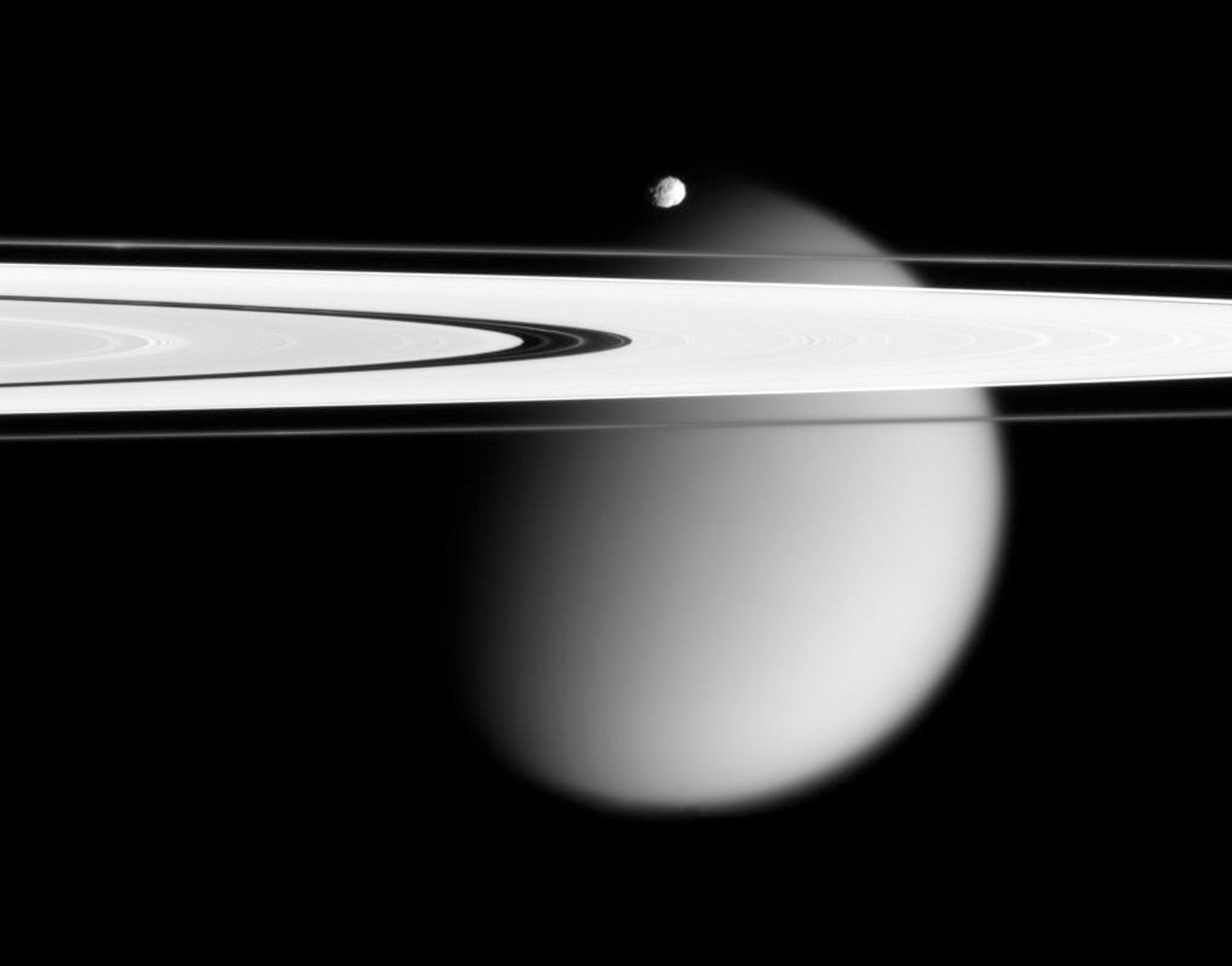This image made by the Cassini spacecraft and provided by NASA on March 12, 2006, shows two of Saturn's moons, the small Epimetheus and smog-enshrouded Titan, with Saturn's A and F rings stretching across the frame