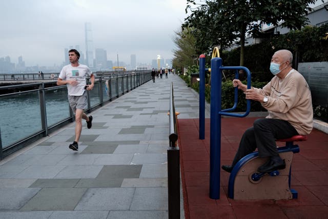 <p>Elderly man exercises while another man jogs past him</p>