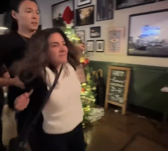 The woman, identified as Shireen Afkari, is removed from the premises by bartender Miguel Marchese