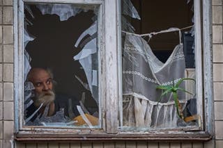 An elderly man looks out of his broken window as an apartment building was hit by a Russian drone during an aerial attack in Kyiv, Ukraine, Tuesday, 23 December