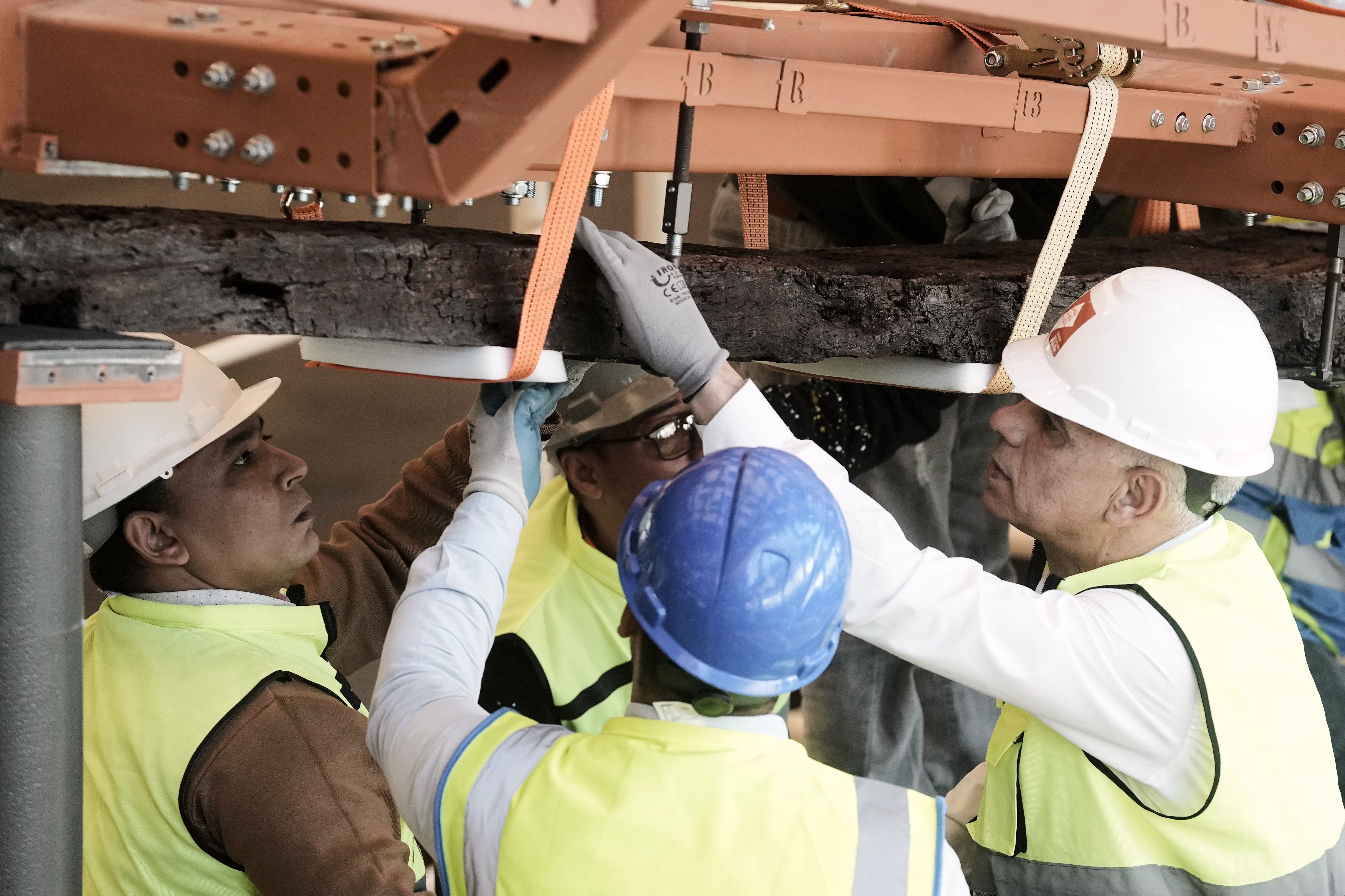 Archeologists carry an ancient wooden block as they reassemble the second solar boat of King Khufu, at the Grand Egyptian Museum in Giza, Egypt, Tuesday, Dec. 23, 2025. (AP Photo/Amr Nabil)