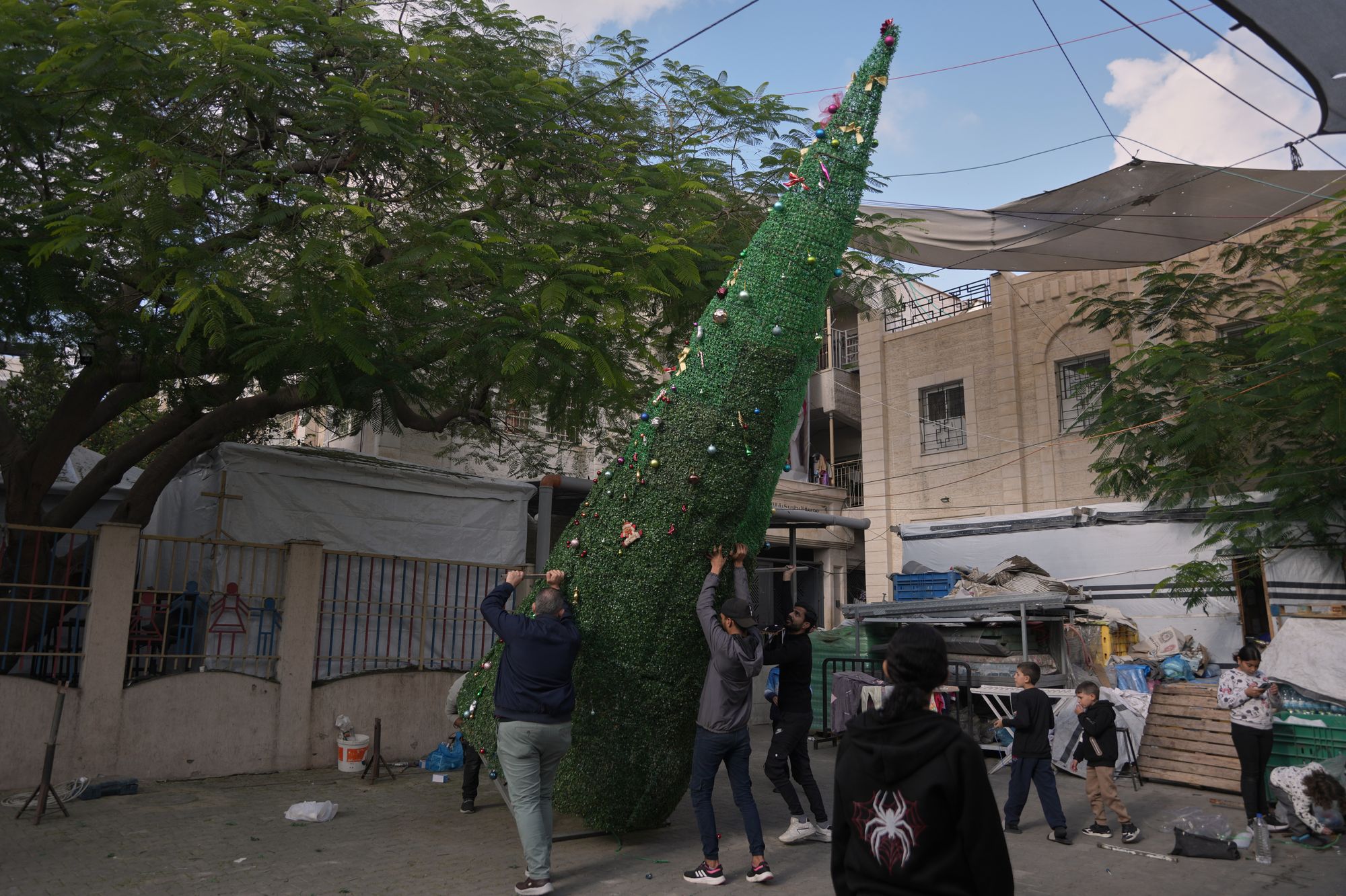 Parishioners put up a Christmas tree they have built at the entrance of the Holy Family Catholic Church