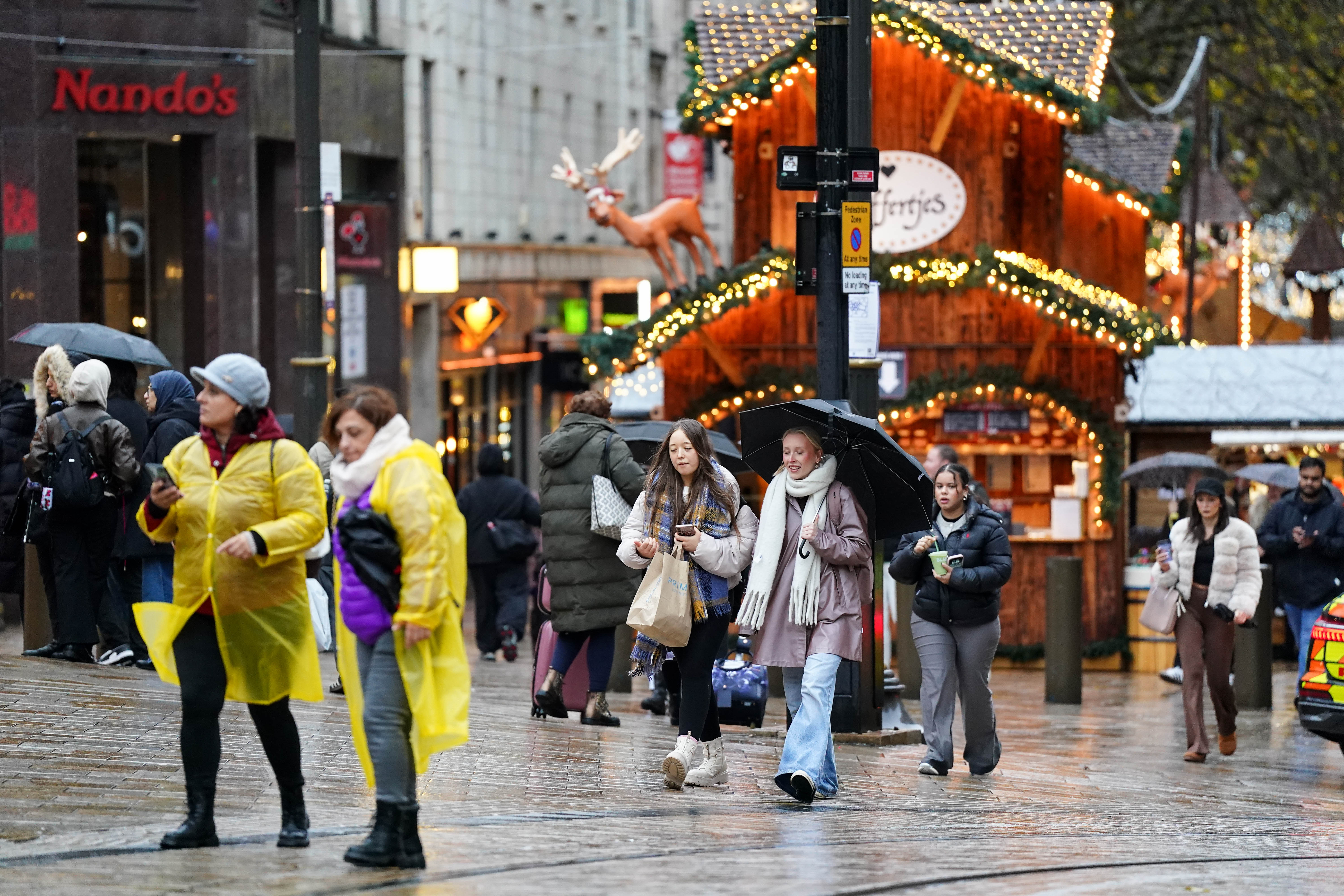People walk by Christmas markets during strong wind in Birmingham
