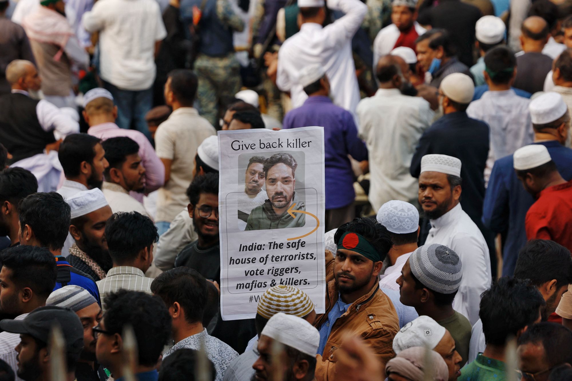 A man holds a placard as tens of thousands of people join the funeral prayer for Sharif Osman Hadi