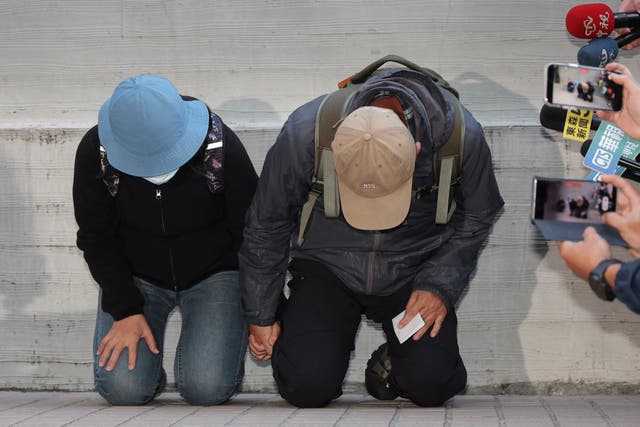 <p>This picture taken and released by Central News Agency (CNA) on 23 December 2025 shows the parents of the suspect in the 19 December Taipei metro stabbings where the attacker killed three and wounded 11, identified by police by his family name Chang and who was later found dead after jumping off a nearby building, kneeling in apology during their appearance at the Taipei City Forensic Inspection and Autopsy Center</p>