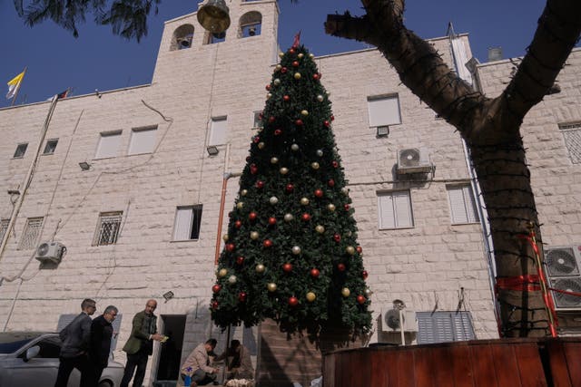 <p>Palestinian parishioners check a recently installed Christmas tree after the previous one was destroyed at the Holy Redeemer Latin Church in the West Bank town of Jenin</p>