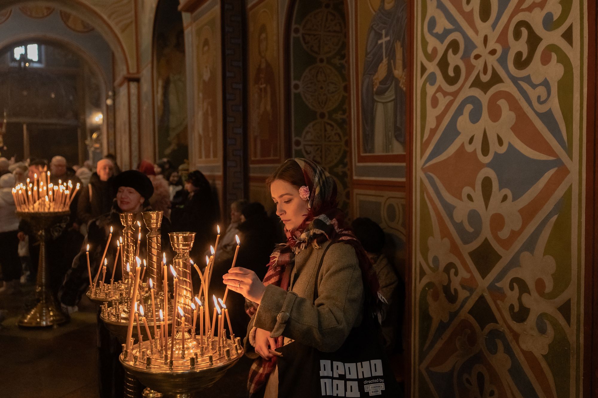 A woman lights a candle during an air strike alarm on Christmas Day at the Saint Michael's Golden-Domed Monastery, in Kyiv