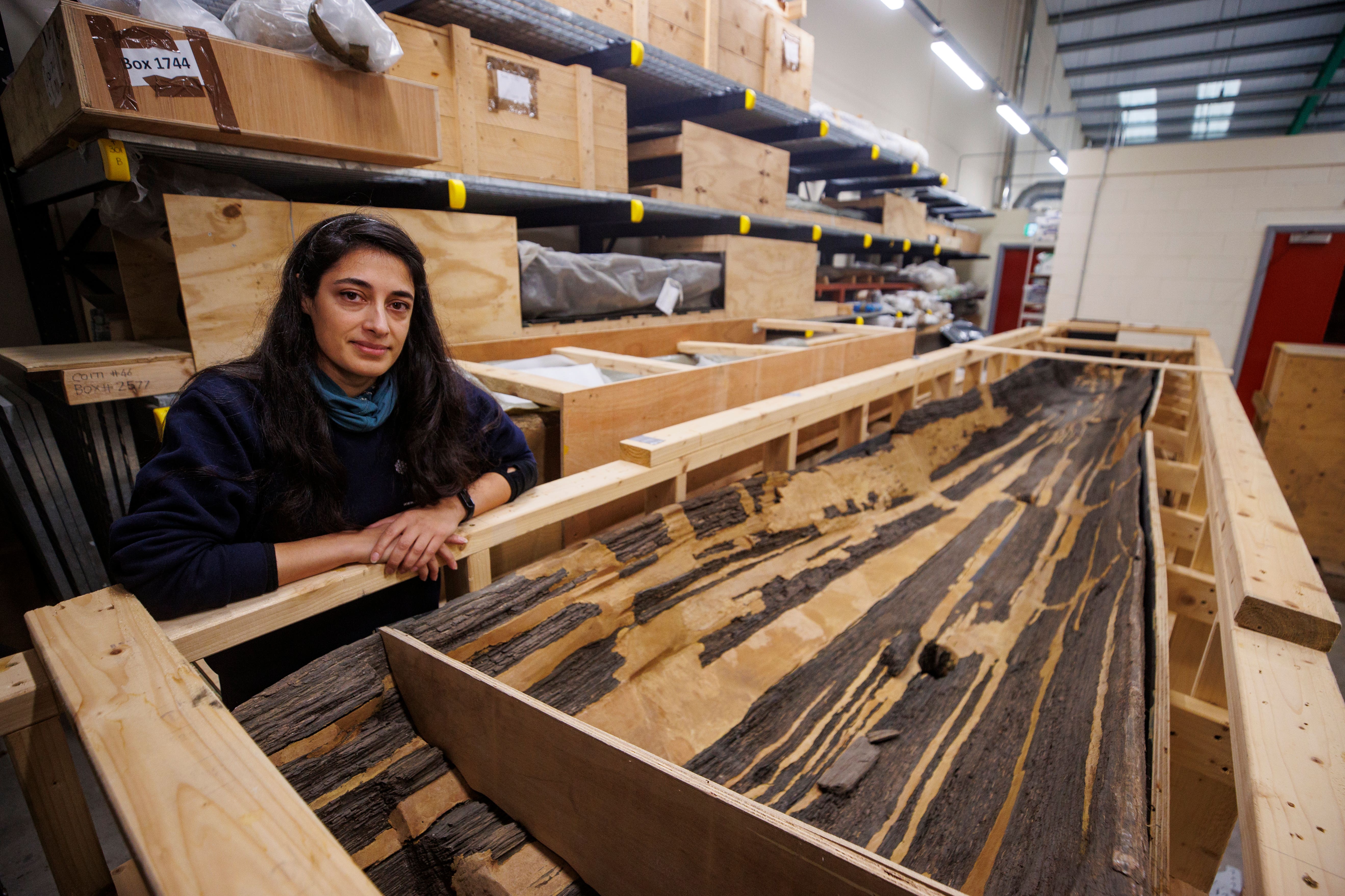 Curatorial archaeologist Sapphire Mussen beside a 7ft, 4,000-year-old log boat that is kept in the archaeological storehouse (Liam McBurney/PA)