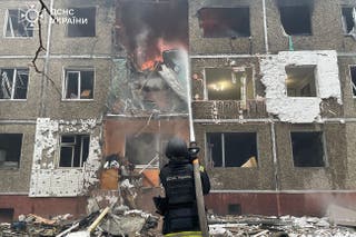 A Ukrainian rescuer extinguishes a fire at a damaged residential building following a drone strike in Chernihiv, amid the Russian invasion of Ukraine