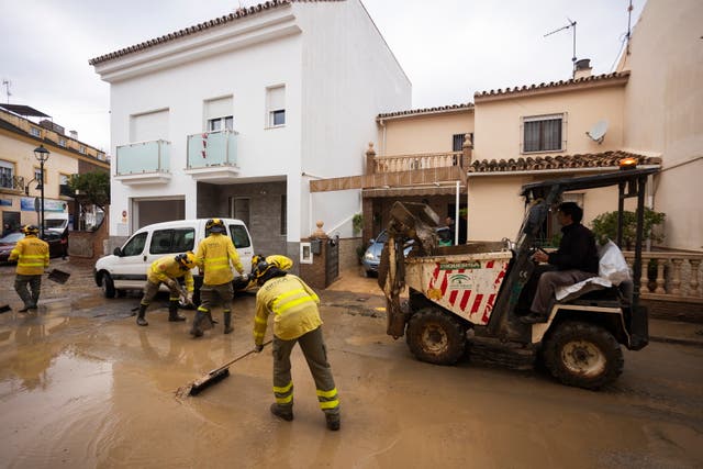 <p>Members of the Andalusian regional forest firefighting unit remove mud from a street in Malaga, southern Spain</p>