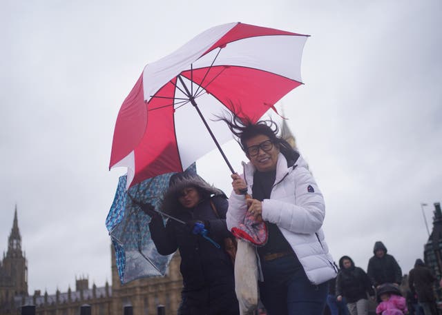 <p>People walk in wind and rain on London’s Westminster Bridge</p>