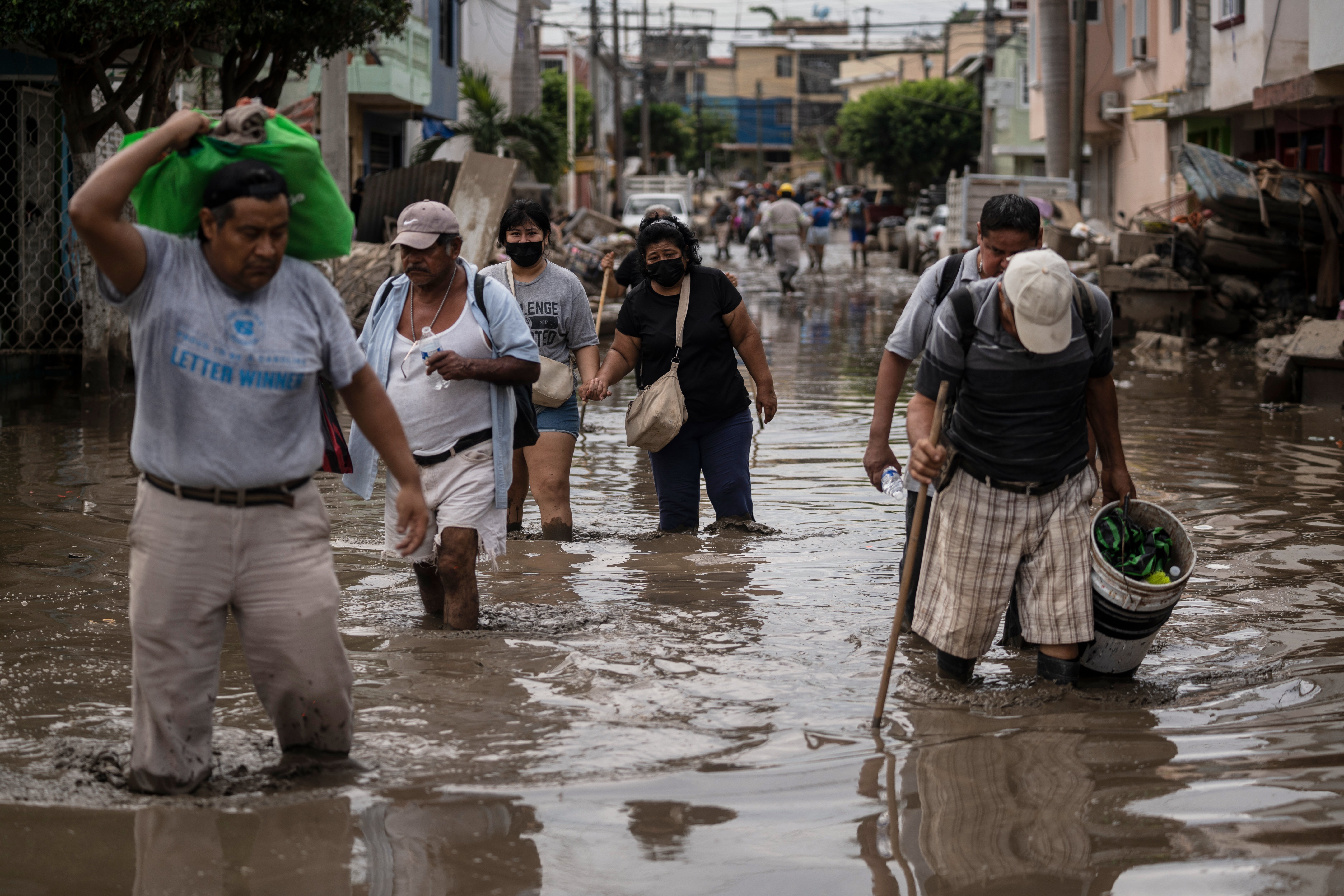 People traverse a flooded street in Poza Rica, Veracruz state, Mexico, Oct. 15, 2025, after torrential rain