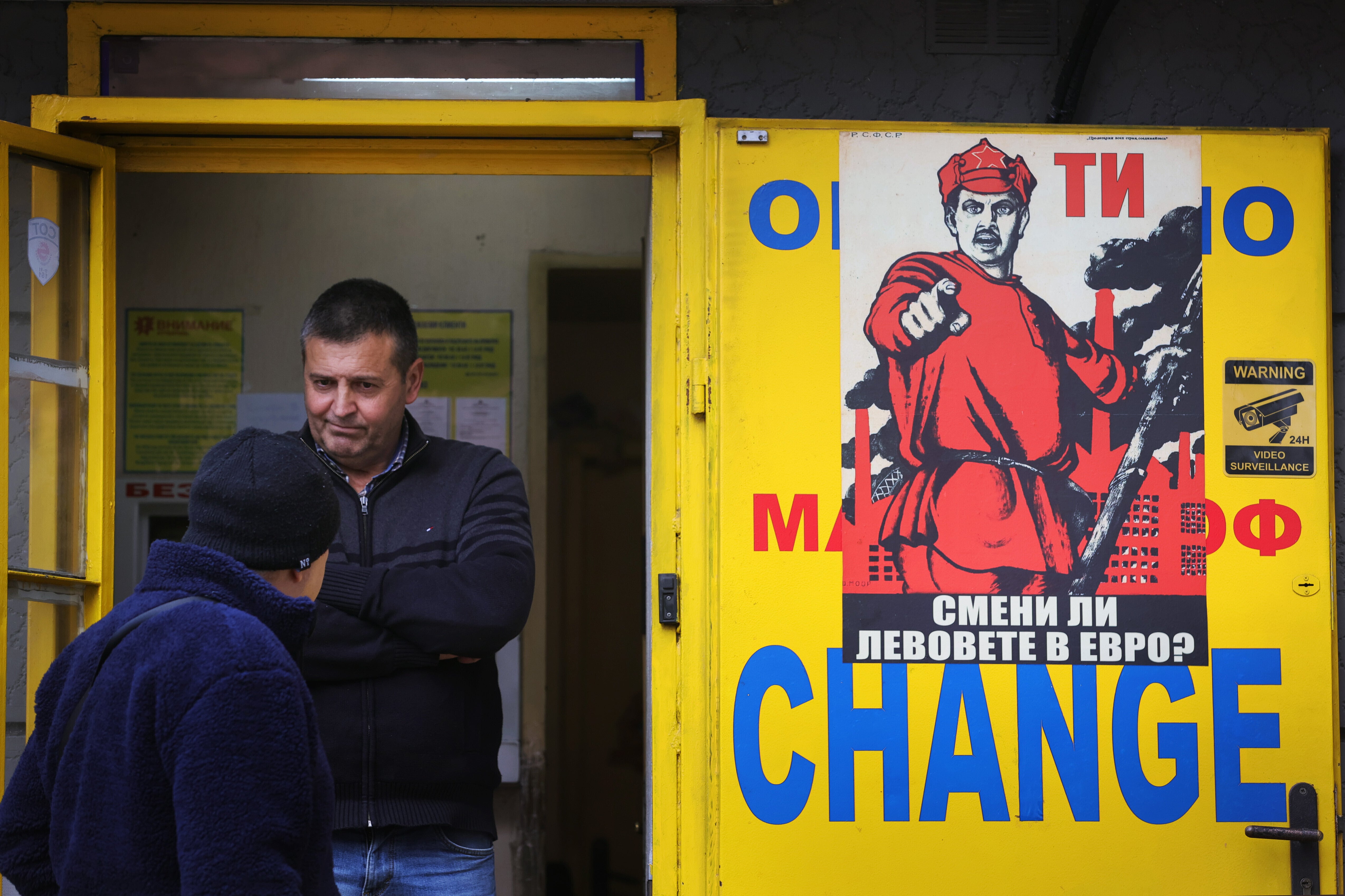 People stand at a currency exchange office with a poster reading "Did you exchange your levs for euros?" in Sofia
