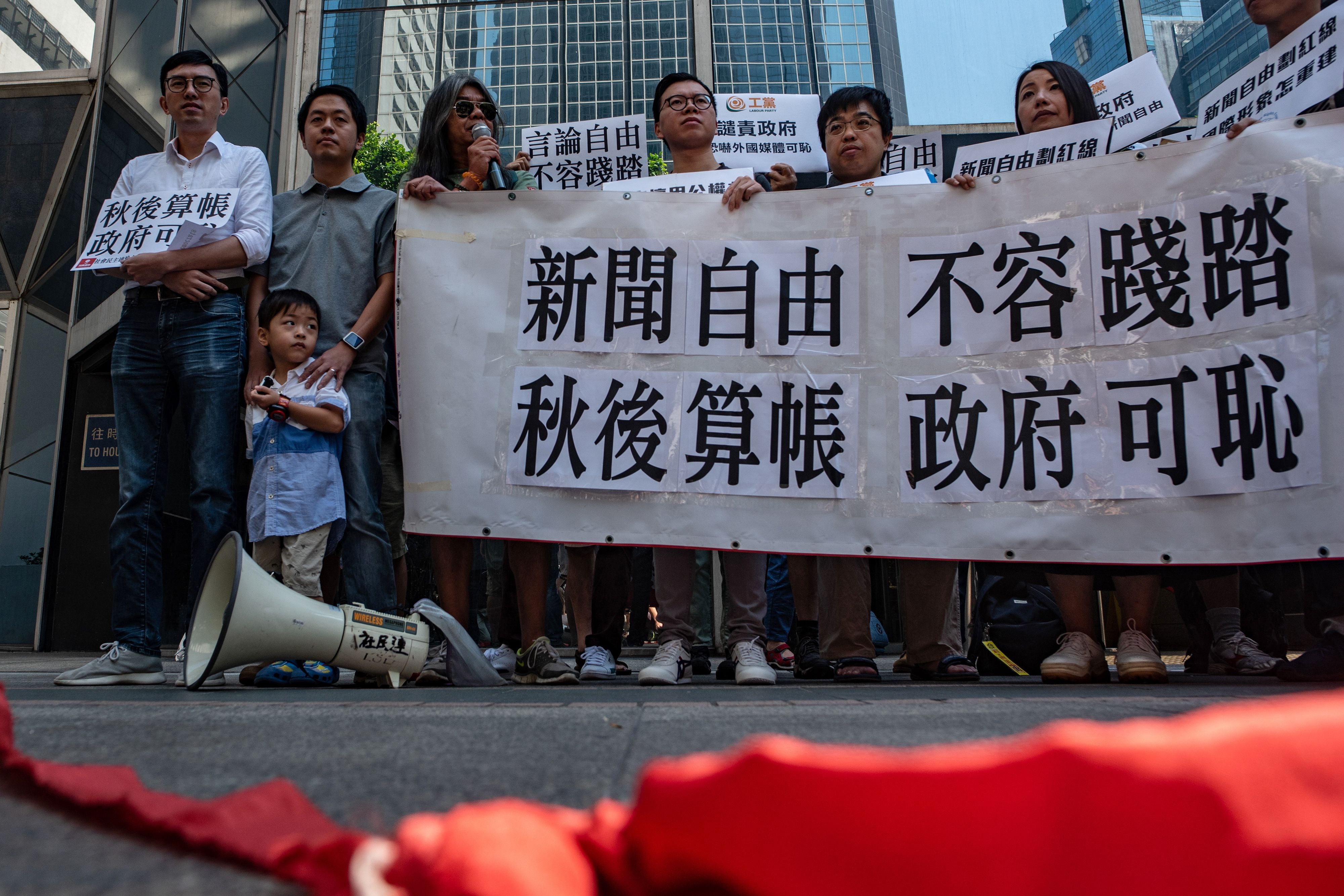 Demonstrators hold a banner that reads 'freedom of the press, not allowed to be trampled' and 'shame on the government's vindictive move' past a symbolic 'political red line' during a protest in 2018