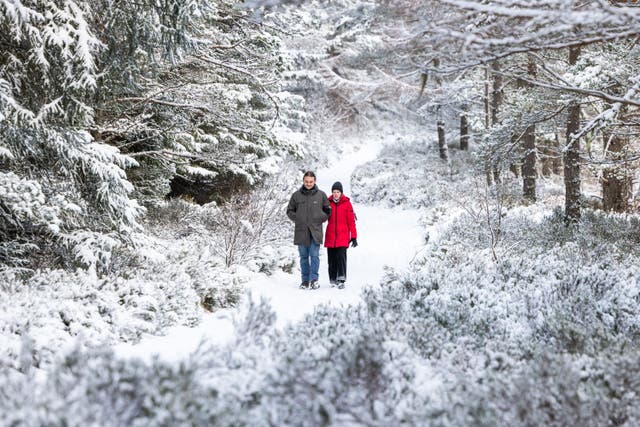 People walking in the snow at Loch Morlich, Aviemore (Paul Campbell/PA)