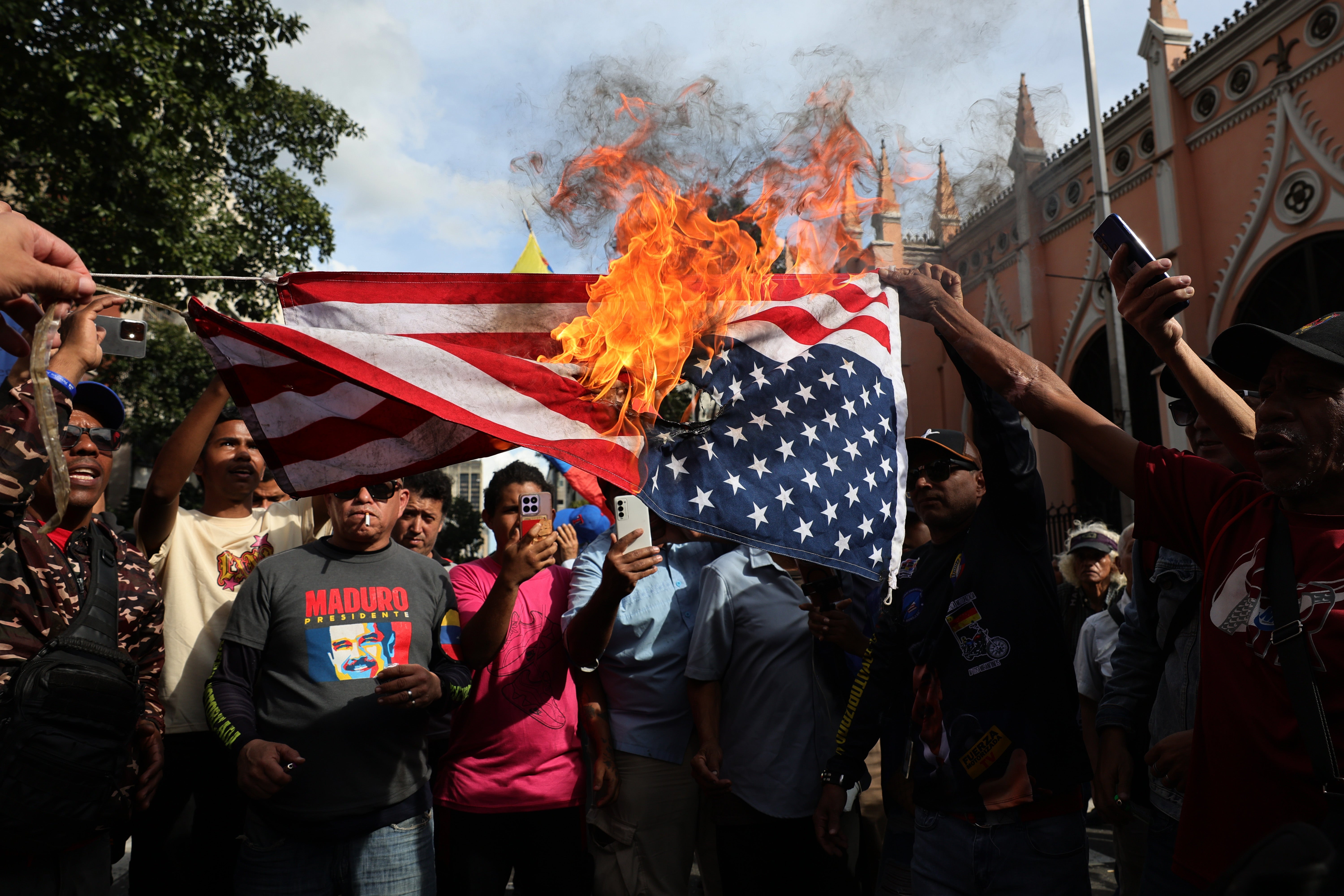 <p>Supporters of captured president Nicolas Maduro in Caracas have been pictured burning the American flag in protest against the U.S. military action in the country</p>