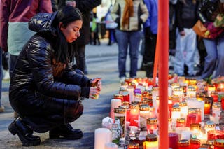 A woman places a candle outside the Le Constellation bar, after a fire and explosion during a New Year's Eve party where people died