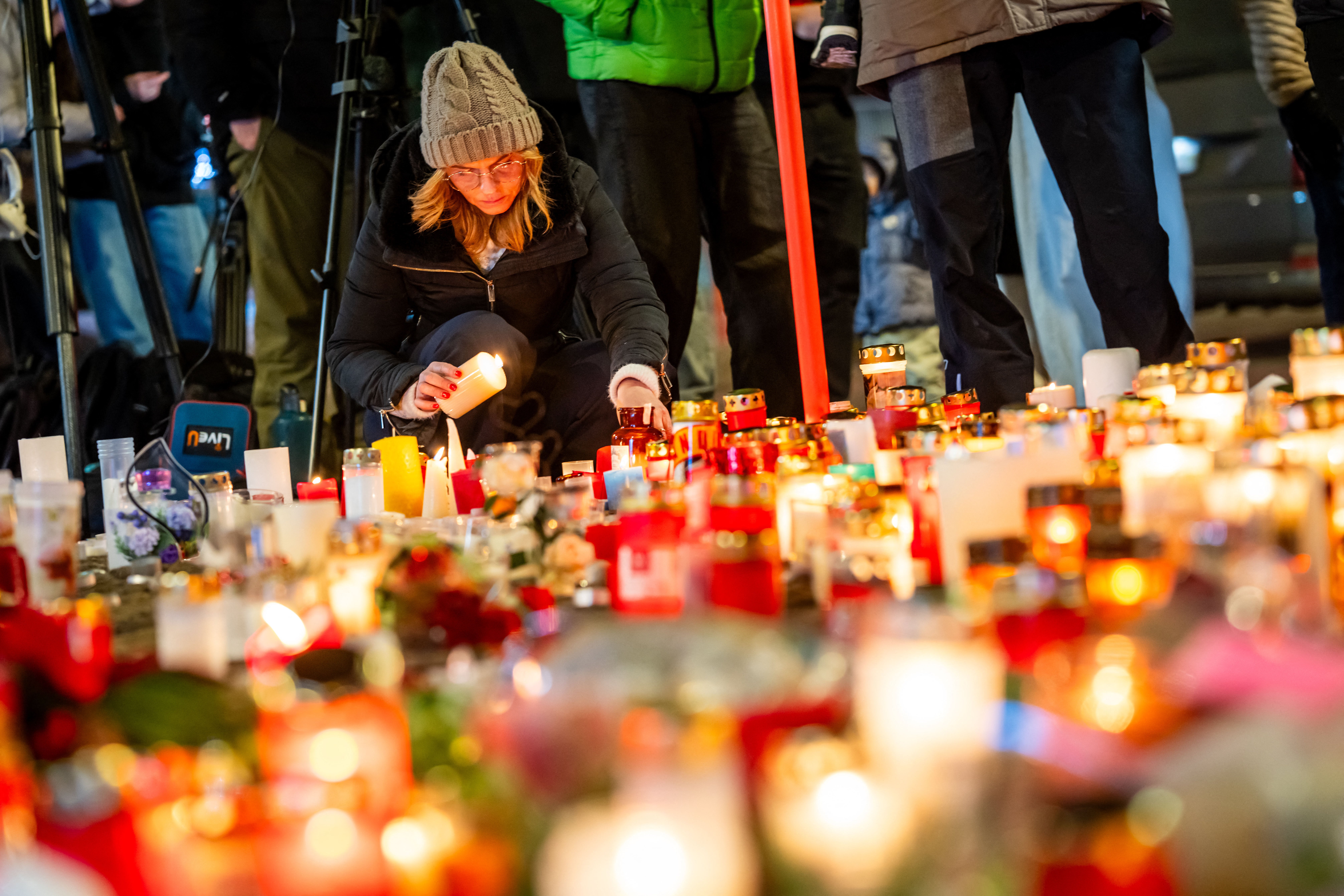 A mourner lights a candle at a makeshift memorial near the site of a fire that ripped through a bar during New Year's Eve celebrations in the Alpine ski resort town of Crans-Montana