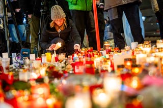 A mourner lights a candle at a makeshift memorial near the site of a fire that ripped through a bar during New Year's Eve celebrations in the Alpine ski resort town of Crans-Montana
