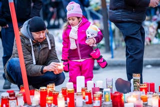 Mourners lay candles near the bar Le Constellation where a fire ripped through the venue during New Year's celebrations