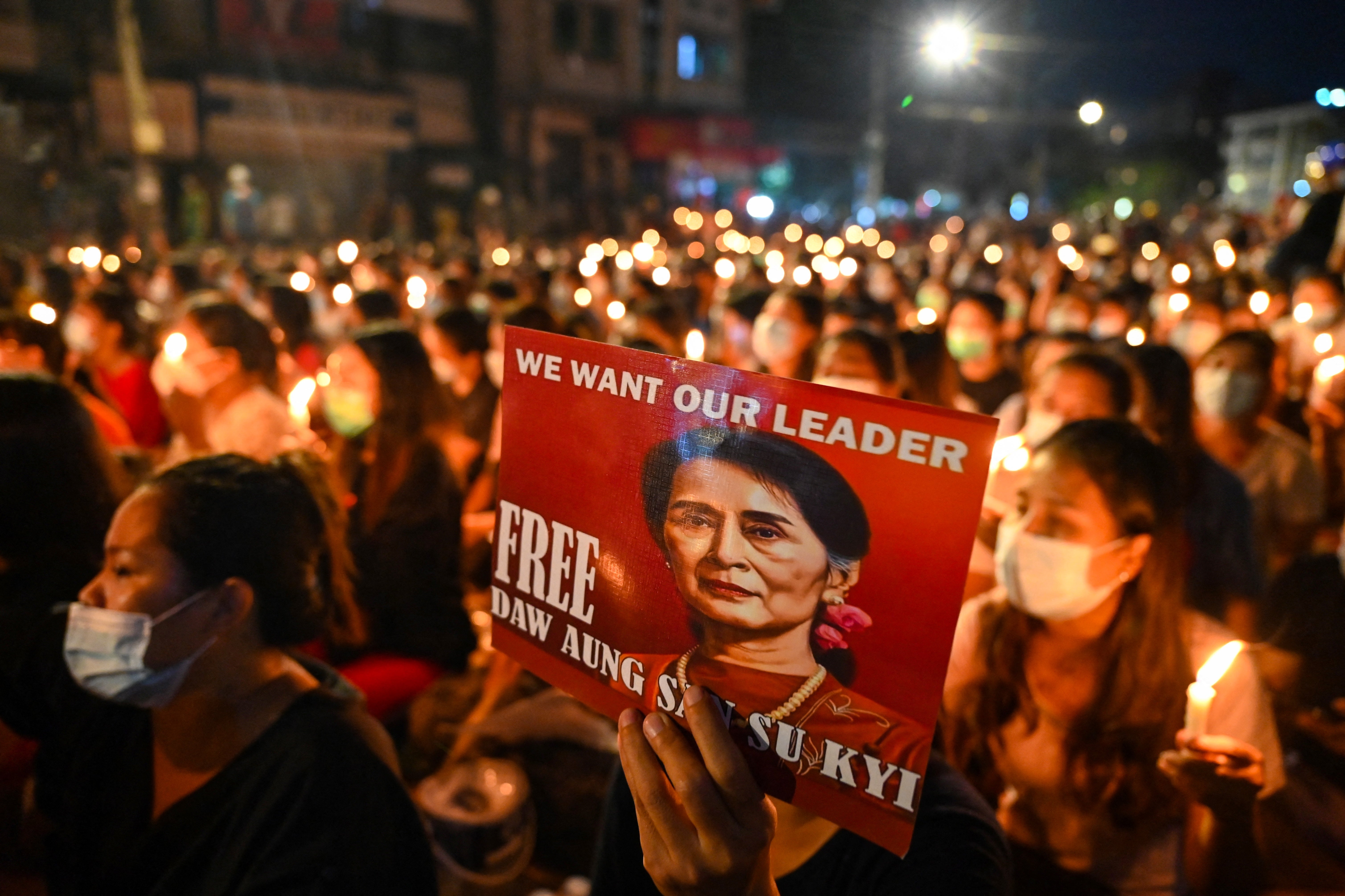 A protester holds a poster with an image of detained civilian leader Aung San Suu Kyi during a candlelight vigil