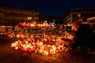 A mourner lights a candle as the investigation continues into the deadly New Year's Eve fire at Le Constellation bar on 3 January 2026 in Crans-Montana, Switzerland