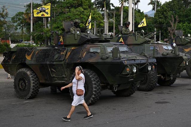 <p>A woman walks past military vehicles at the border crossing with Venezuela in Cucuta </p>