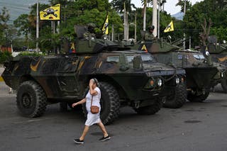 A woman walks past military vehicles at the border crossing with Venezuela in Cucuta, Colombia, on 3 January 2026, after US forces captured Venezuela's President Nicolas Maduro