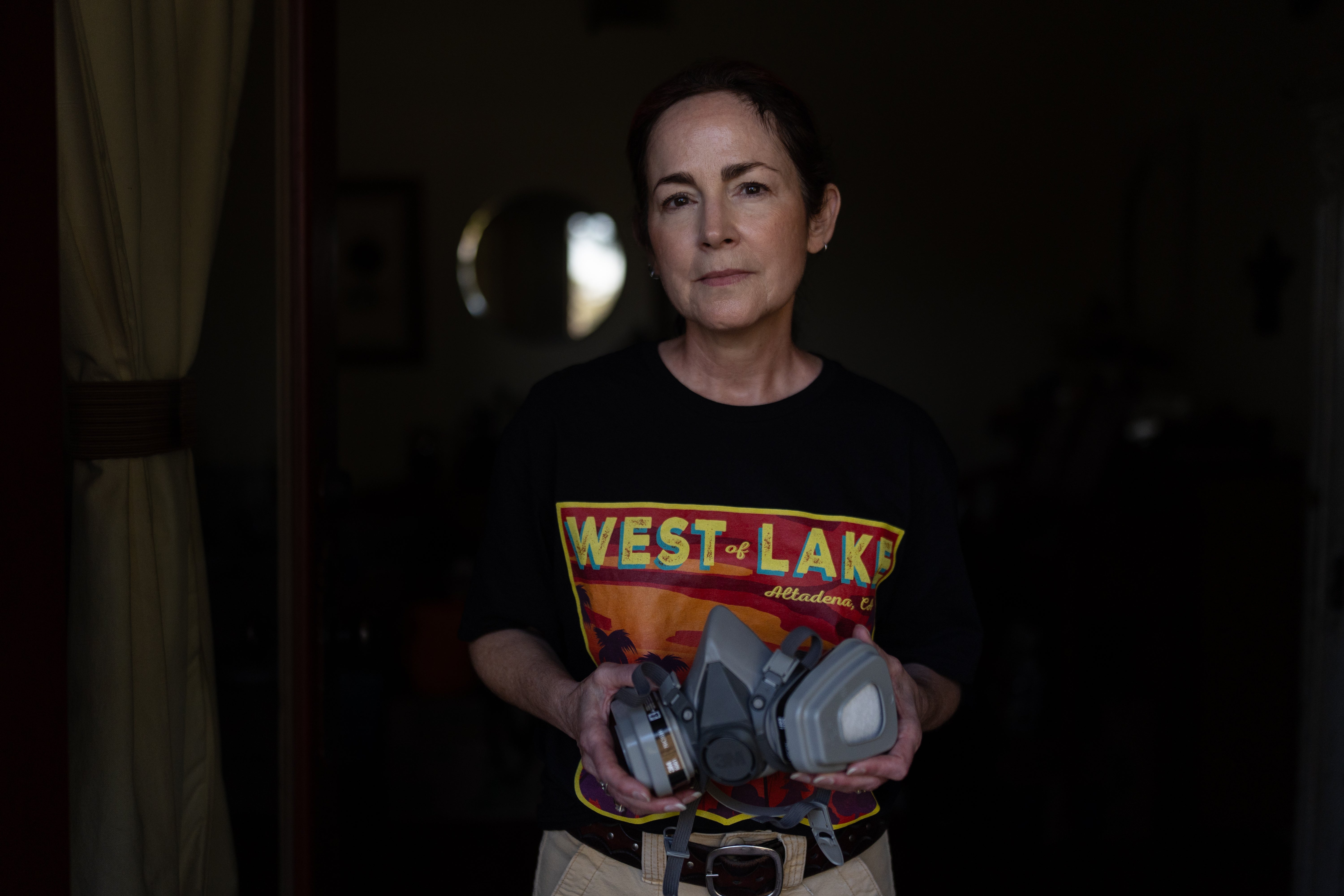 Nina Malone, whose home survived the Eaton Fire, stands for a photo with a respirator she uses when cleaning fire debris inside her home, Dec. 11, 2025, in Altadena, Calif. (AP Photo/Jae C. Hong)