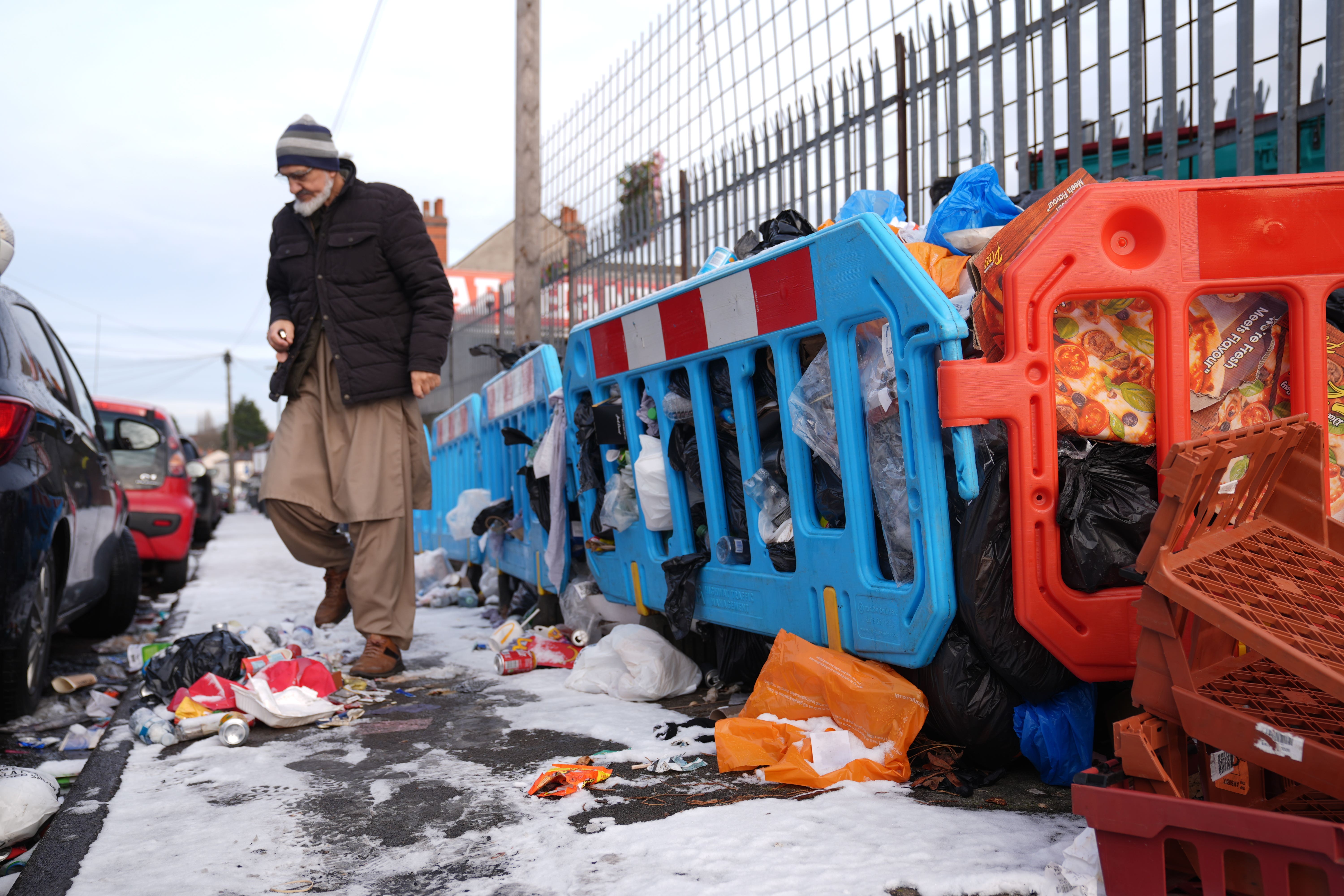 A person walks among piles of uncollected refuse bags and household waste in the Saltley area of Birmingham (Joe Giddens/PA)