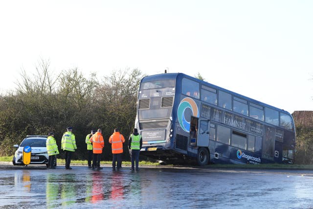 <p>Police at the scene after a bus crashed into a ditch near Ashford in Kent</p>