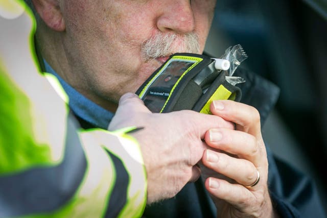 A driver blows into a breathalyser during a checkpoint (PA)