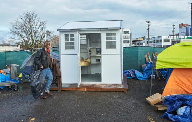 <p>A man moves his belongings into a pod setup by the city in Portland, Oregon</p>