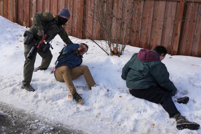 <p>An ICE agent restrains protesters who were attempting to block vehicles from leaving the scene where a person was reportedly shot in Minneapolis </p>