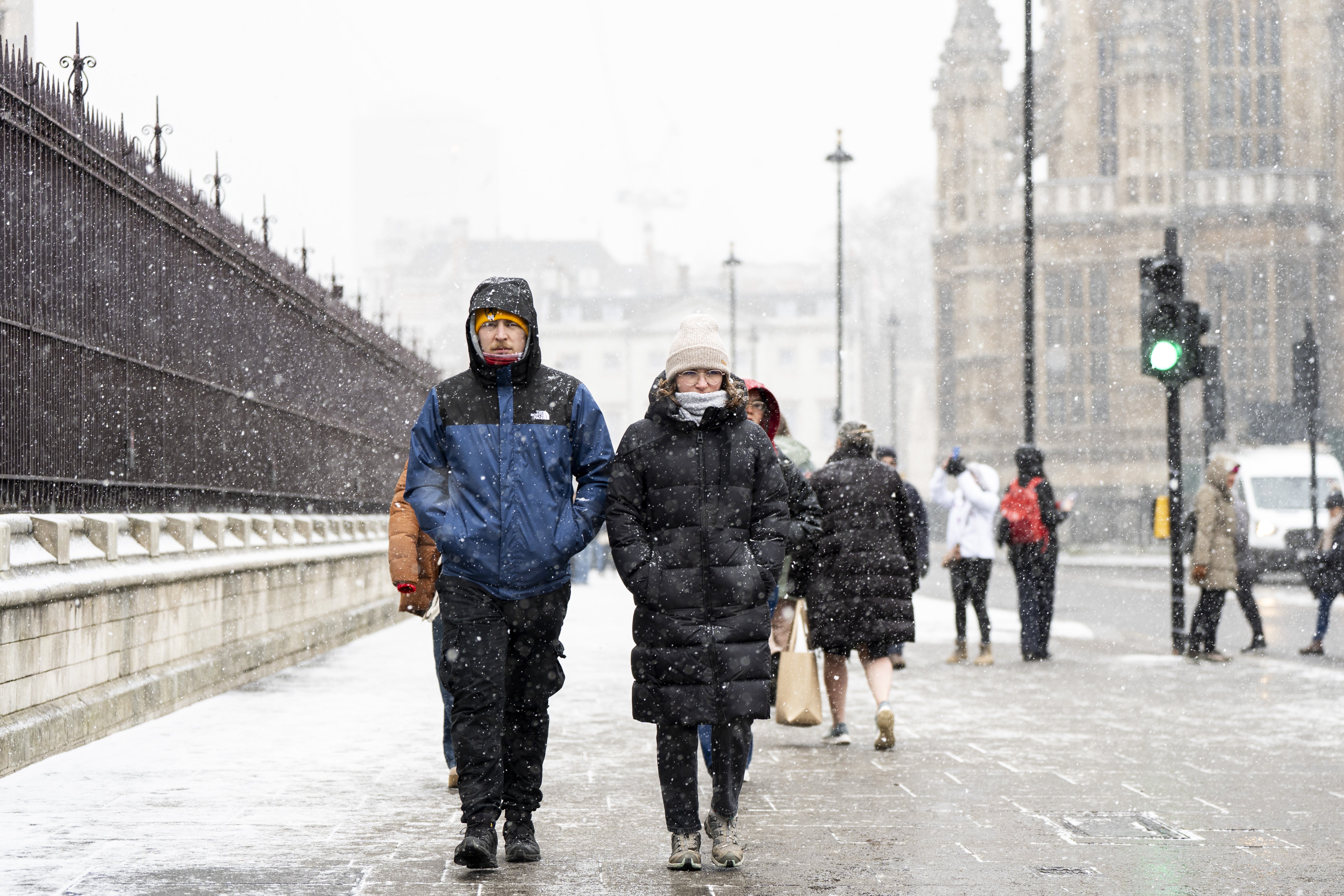 <p>People in snowy conditions in Westminster, central London</p>